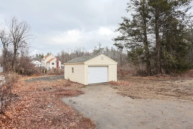 a view of white house with large trees and wooden fence