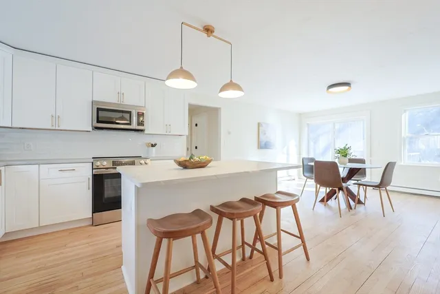 a kitchen with stainless steel appliances granite countertop a stove a sink a microwave a dining table and chairs with wooden floor