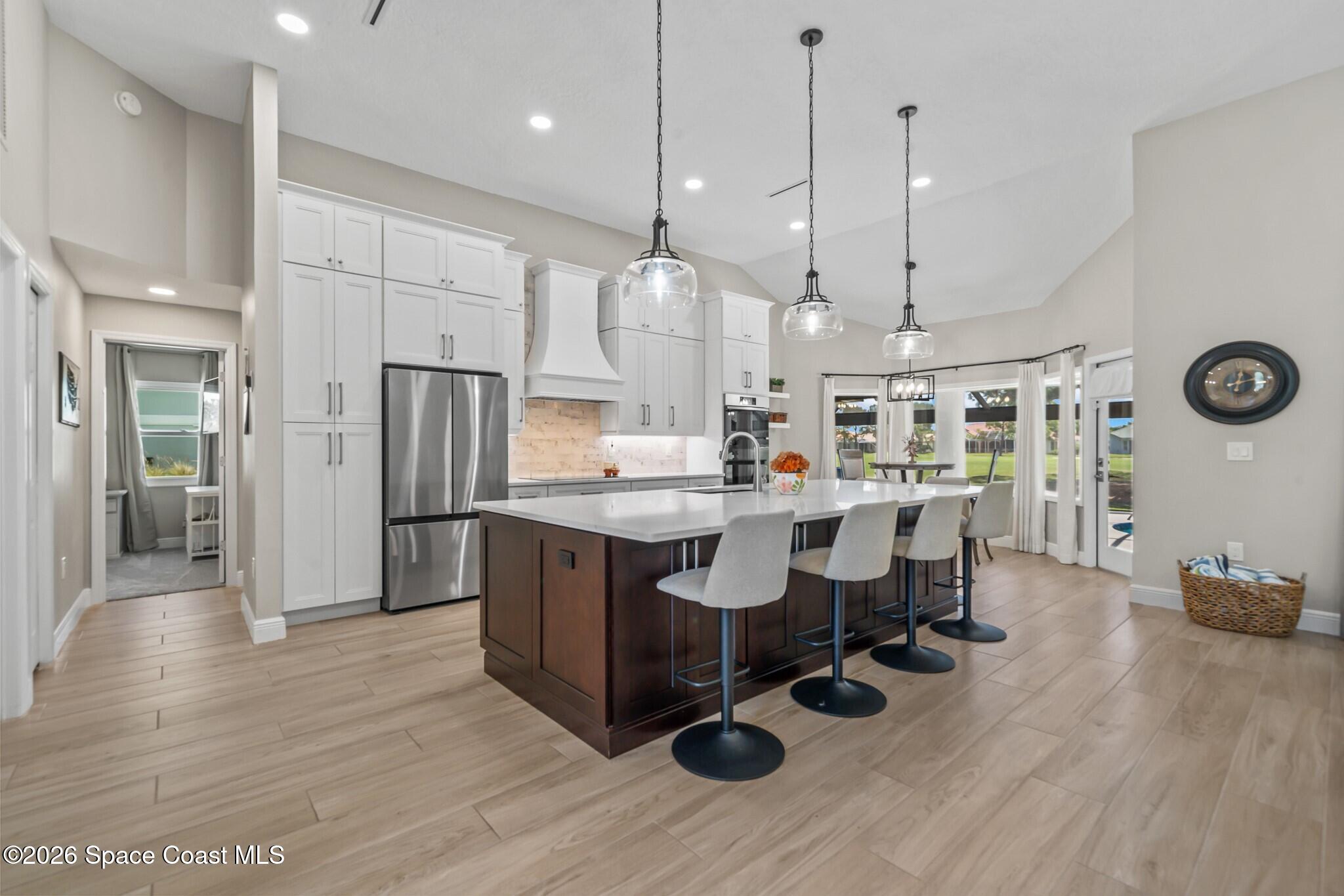 697 Spring Lake Drive Melbourne, FL 32940 - Photo 10 of 45 a kitchen with stainless steel appliances kitchen island granite countertop a table chairs and a refrigerator