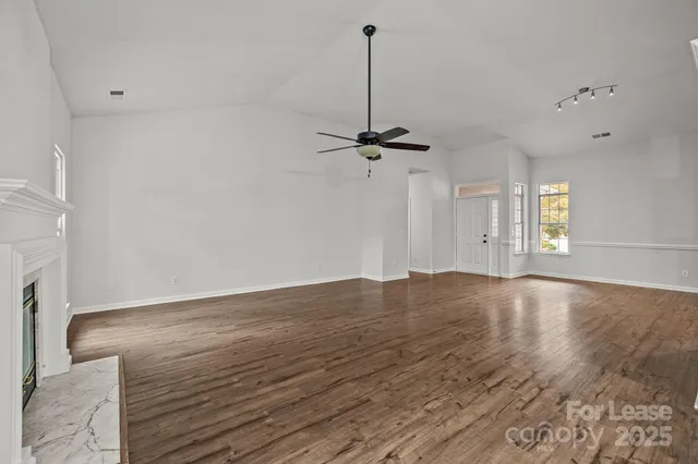 a view of a room with a ceiling fan and hardwood floor