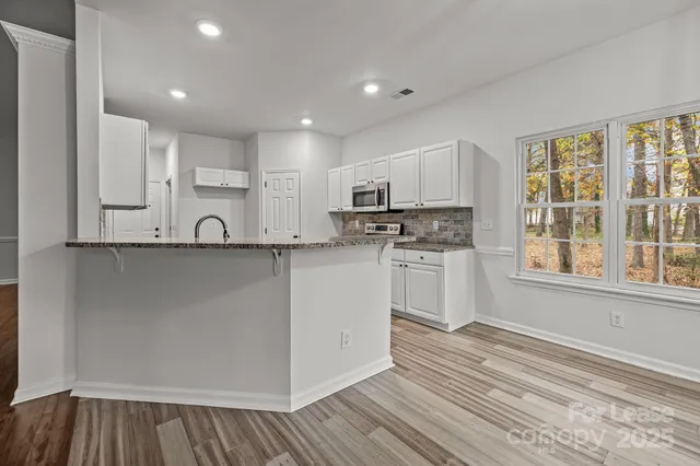 a kitchen with kitchen island white cabinets and wooden floor