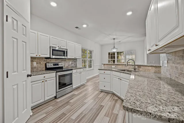 a kitchen with granite countertop a sink stainless steel appliances and cabinets