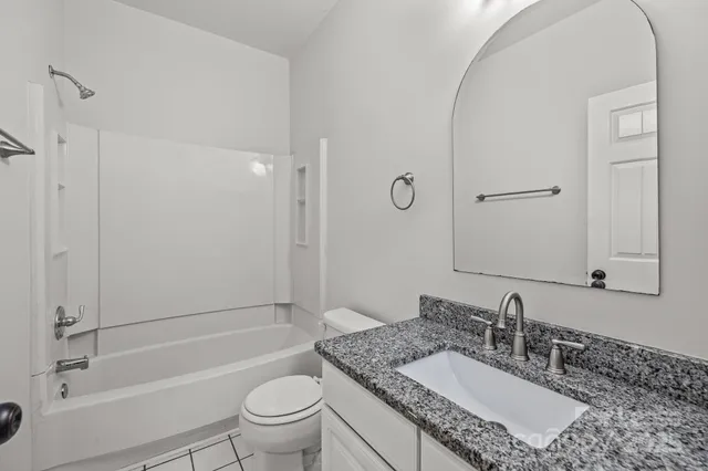 a bathroom with a granite countertop sink a toilet and shower