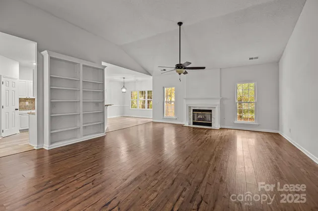 an empty room with wooden floor fireplace and windows