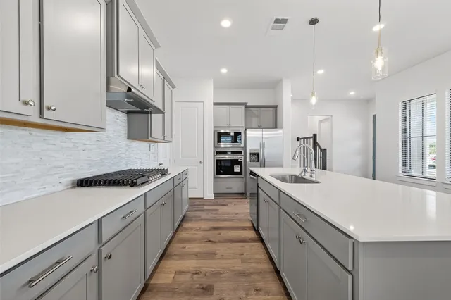 a large kitchen with stainless steel appliances lots of counter space and wooden floor