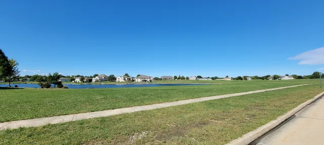 a view of a field with lawn chairs and trees