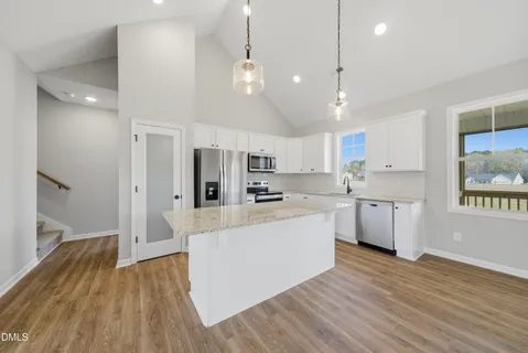 a large kitchen with stainless steel appliances granite countertop a large center island attached withe living room
