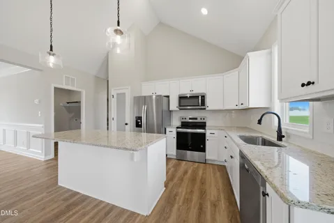 a large kitchen with stainless steel appliances granite countertop a lot of counter space and wooden floors