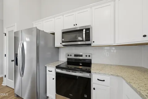 a kitchen with stainless steel appliances granite countertop white cabinets and a granite counter tops