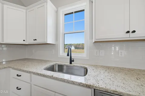 a kitchen with granite countertop white cabinets and a sink
