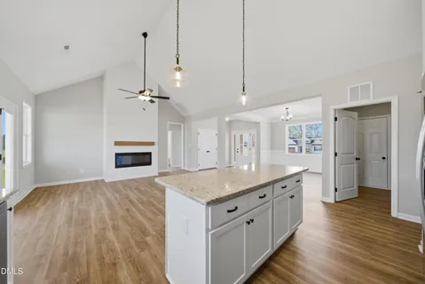 a hall with kitchen island a stove a sink dishwasher and a fireplace with wooden floor