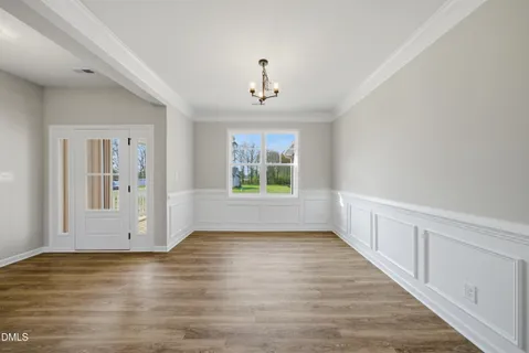 a view of an empty room with window wooden floor and a kitchen