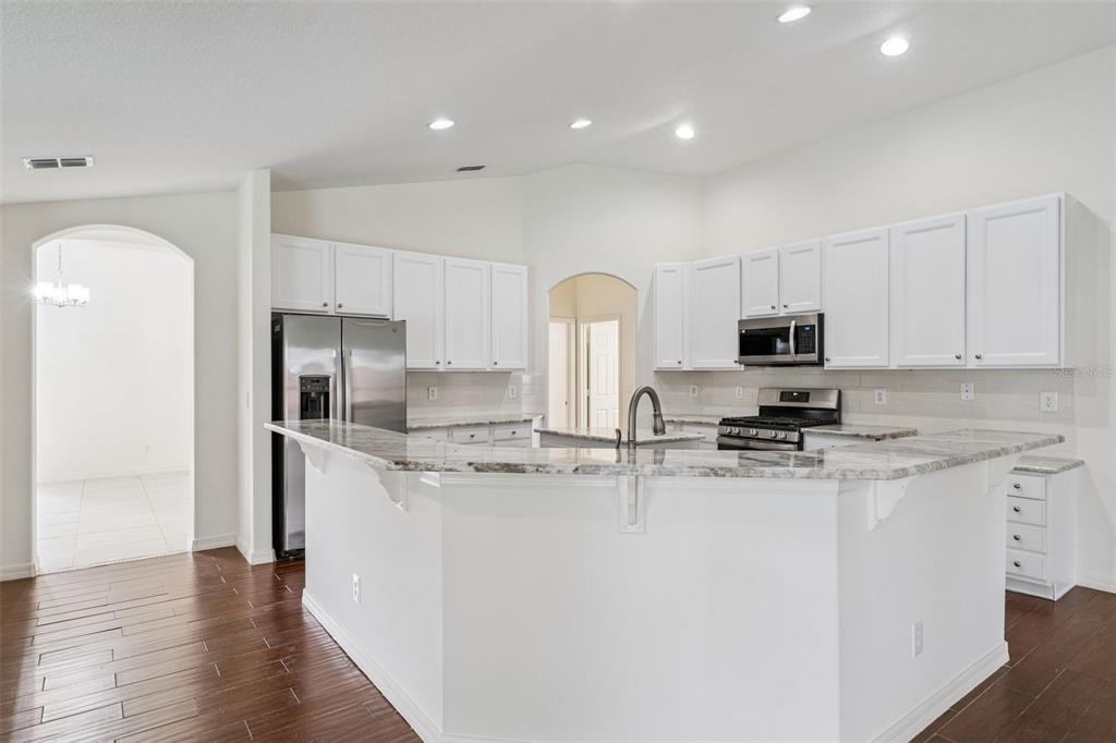 2440 Holly Ridge Court Clermont, FL 34711 - Photo 7 of 43 a kitchen with stainless steel appliances granite countertop a refrigerator a stove a sink a microwave a refrigerator and white cabinets with wooden floor