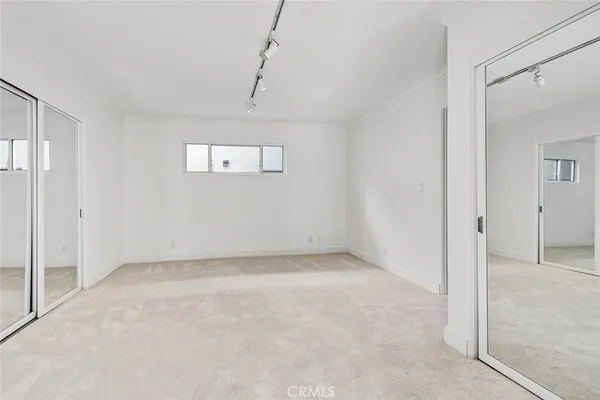 a view of an empty room with closet and wooden floor