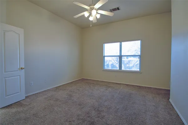an empty room with a window and a fan