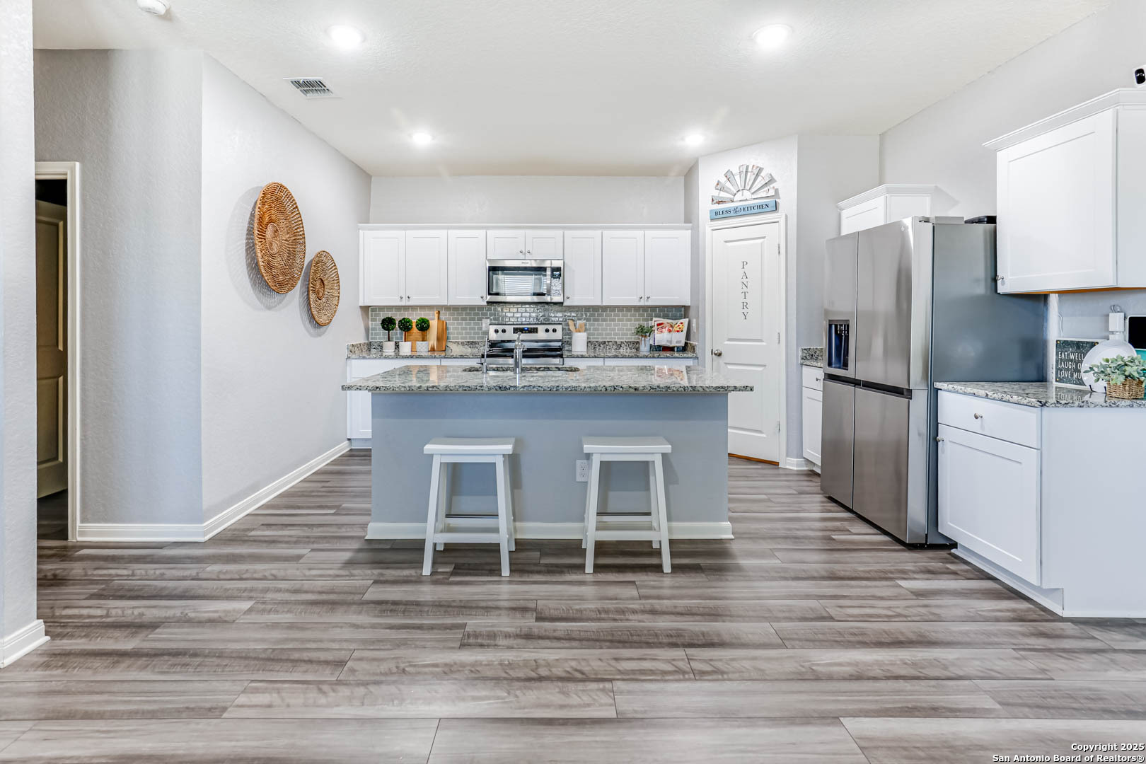 14383 Palm Ridge San Antonio, TX 78253 - Photo 12 of 45 a kitchen with stainless steel appliances granite countertop a kitchen island a stove a refrigerator with white cabinets and wooden floor
