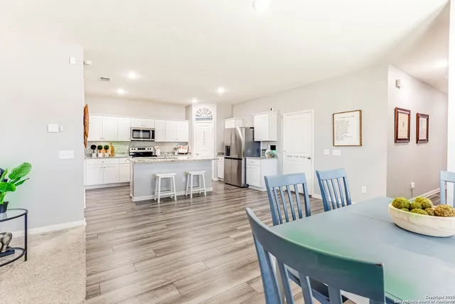 a kitchen with stainless steel appliances kitchen island granite countertop a table chairs and a view of living room