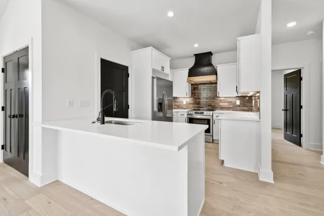 a kitchen with kitchen island granite countertop a sink and a refrigerator