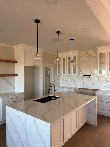 a kitchen with stainless steel appliances granite countertop a sink a island and a wooden floor