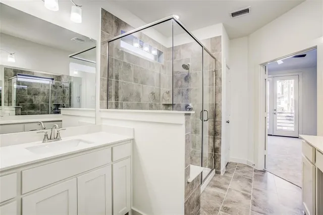 a bathroom with a granite countertop sink a mirror and shower