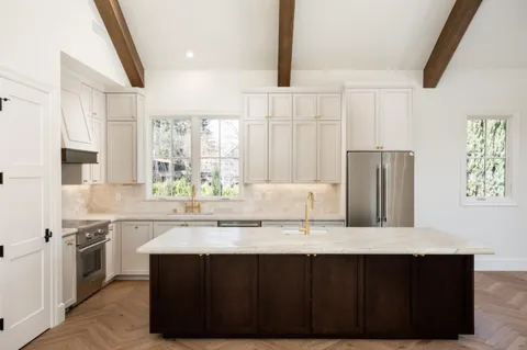 a kitchen with stainless steel appliances granite countertop a stove a sink dishwasher and a refrigerator with wooden floor