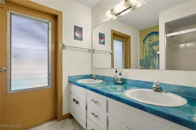 a bathroom with a granite countertop double vanity sink and a mirror