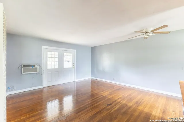 a view of empty room with wooden floor and fan