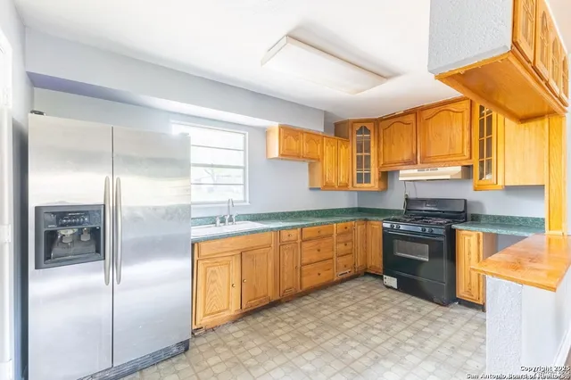 a kitchen with stainless steel appliances granite countertop a refrigerator a sink a stove with wooden cabinets