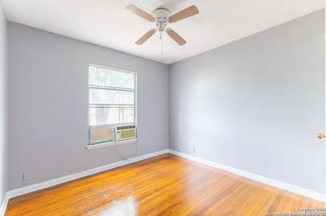 an empty room with windows and ceiling fan