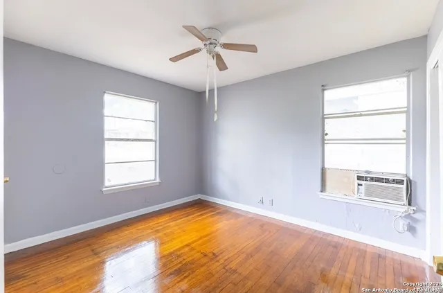 a view of empty room with wooden floor and fan