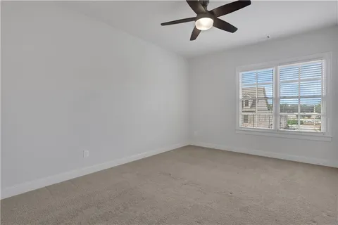 an empty room with a ceiling fan and window