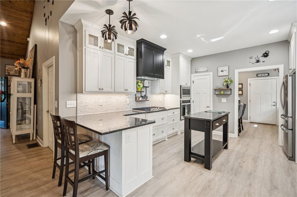305 Wilkie Road Ball Ground, GA 30107 - Photo 14 of 37 a kitchen with stainless steel appliances kitchen island granite countertop a table chairs refrigerator and sink