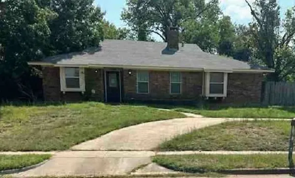 a view of a brick house with a yard and large tree