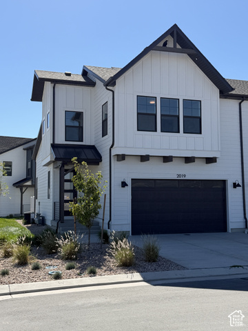 Modern exterior with vertical white siding, black-framed windows, a black garage door, and decorative wood accents