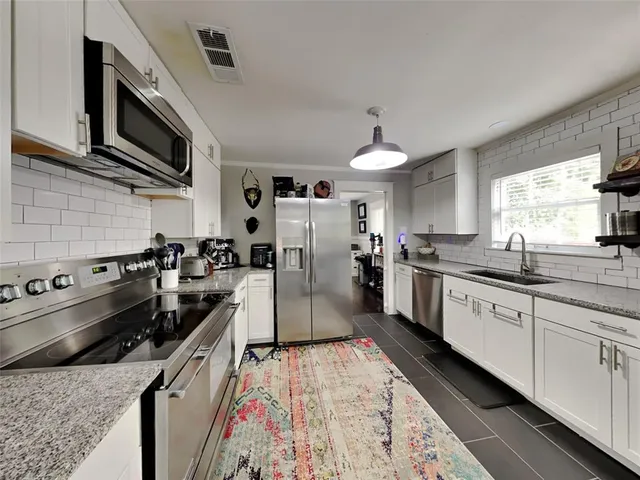 a large kitchen with stainless steel appliances granite countertop a stove and a sink