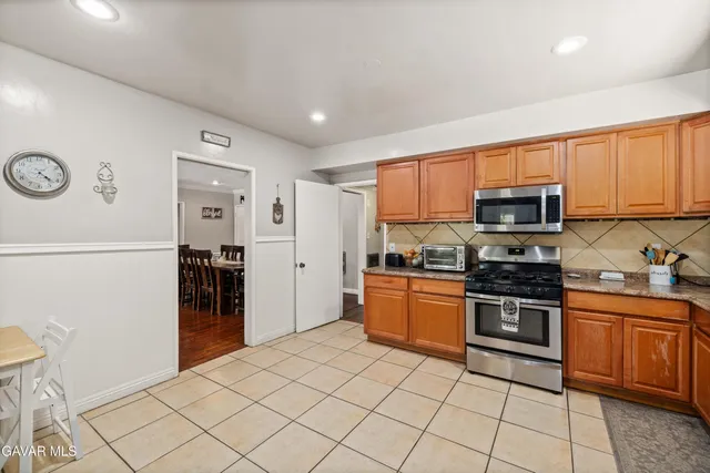 a kitchen with stainless steel appliances granite countertop a refrigerator and a stove top oven