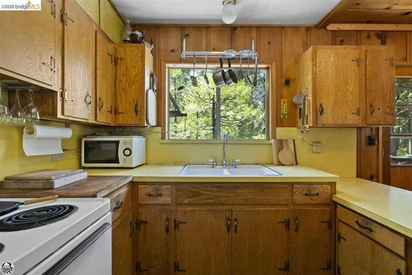 a utility room with stainless steel appliances a stove a sink and a microwave