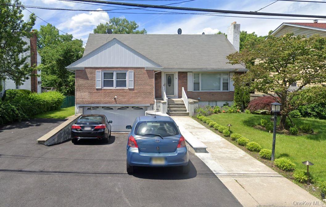 a front view of a house with a garden and parking