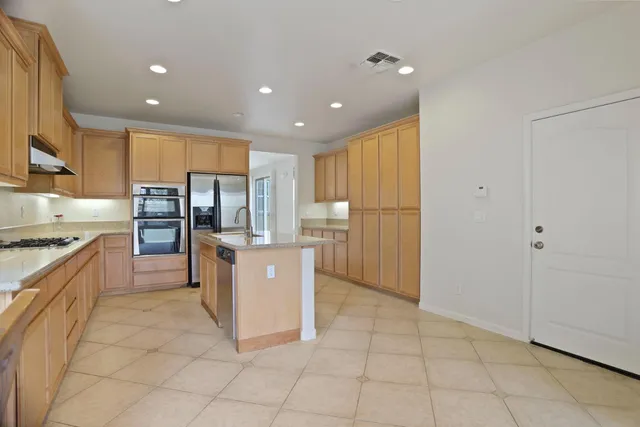 a kitchen with stainless steel appliances granite countertop a refrigerator and a stove top oven