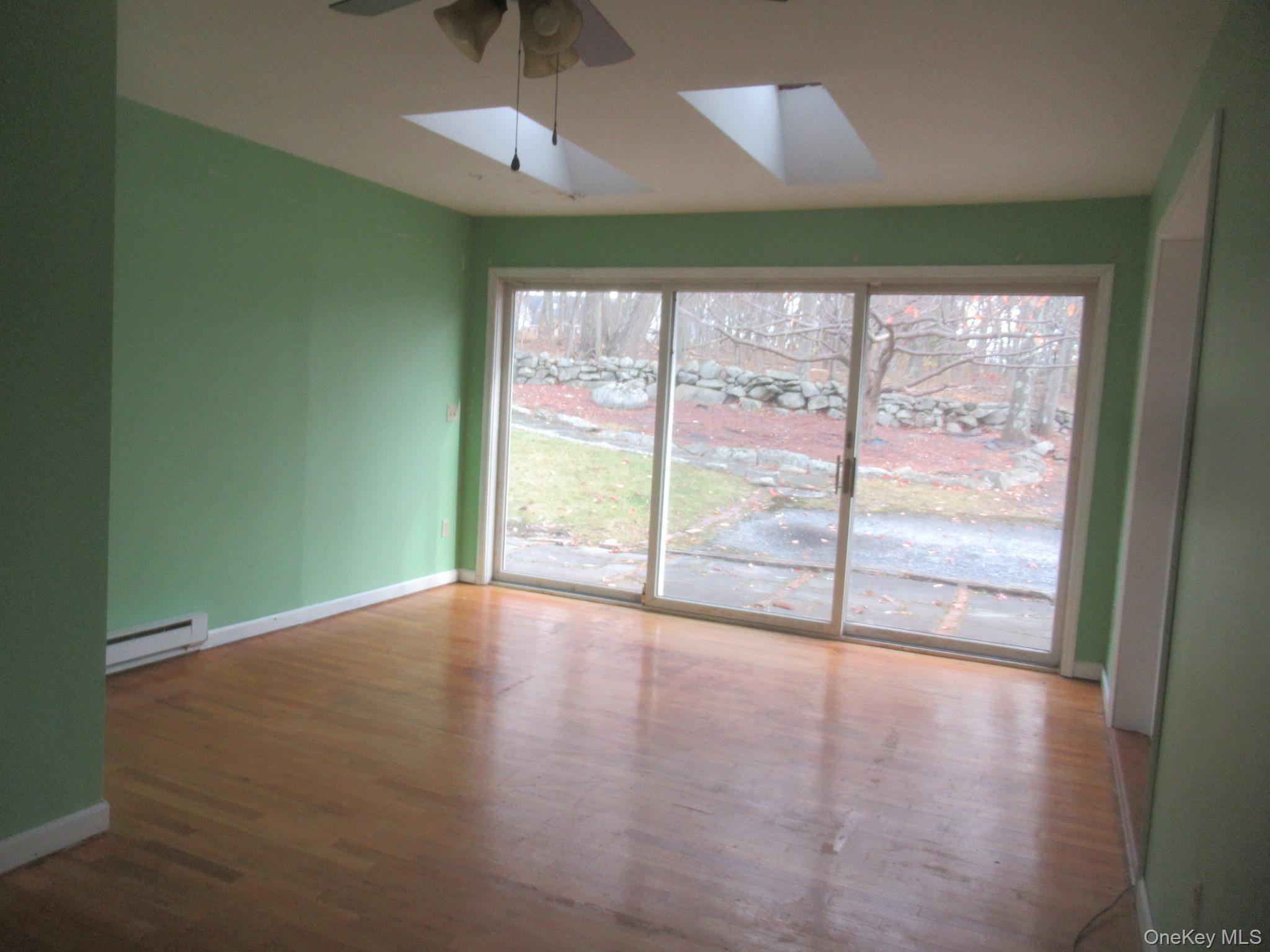 64 Hillside View Road Mahopac, NY 10541 - Photo 13 of 23 Unfurnished room featuring a baseboard heating unit, dark wood finished floors, and a skylight