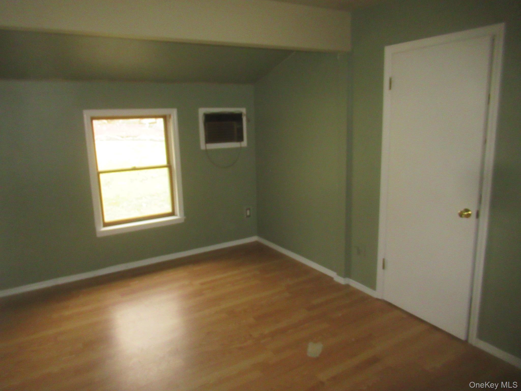 64 Hillside View Road Mahopac, NY 10541 - Photo 9 of 23 Unfurnished room with wood finished floors, lofted ceiling, and a wall mounted air conditioner