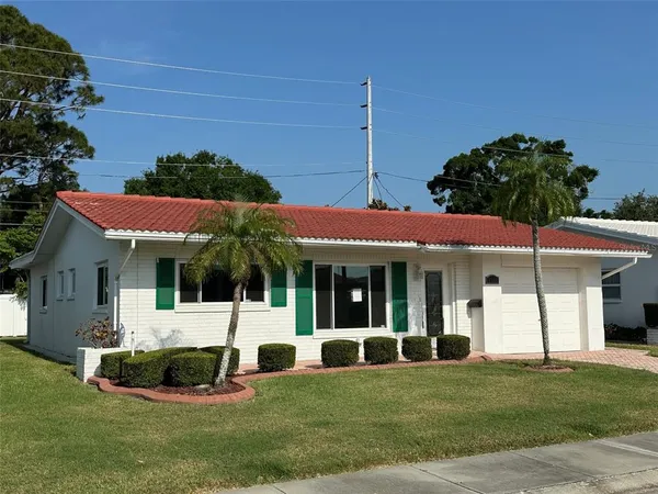 a view of a white house with a big yard and potted plants