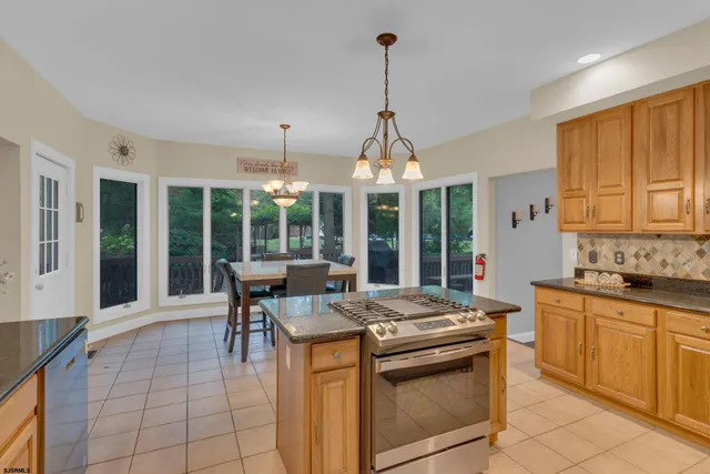 a kitchen with stainless steel appliances granite countertop a stove and a view of living room