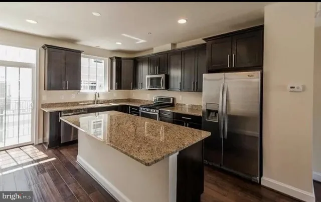 a kitchen with stainless steel appliances granite countertop a refrigerator a sink and a stove
