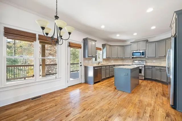 a kitchen with stainless steel appliances granite countertop a refrigerator a sink dishwasher a stove and white countertops with wooden floor