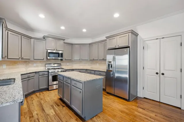 a kitchen with stainless steel appliances granite countertop a refrigerator a stove a sink and a microwave