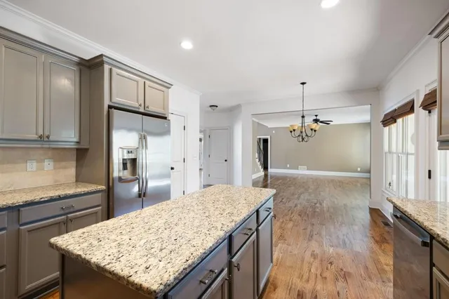 a kitchen with granite countertop a stove a sink a refrigerator and wooden cabinets