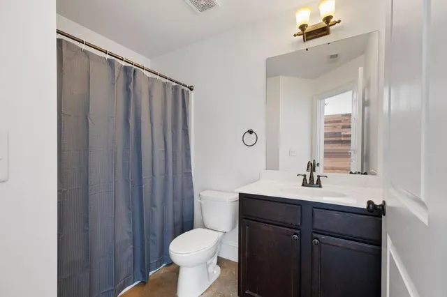 a bathroom with a sink a toilet a mirror and shower curtain