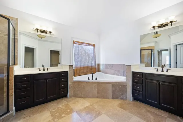 a spacious bathroom with a tub sink double vanity and mirror