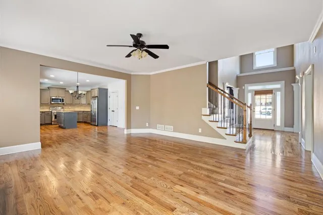 a view of an empty room with wooden floor and a kitchen